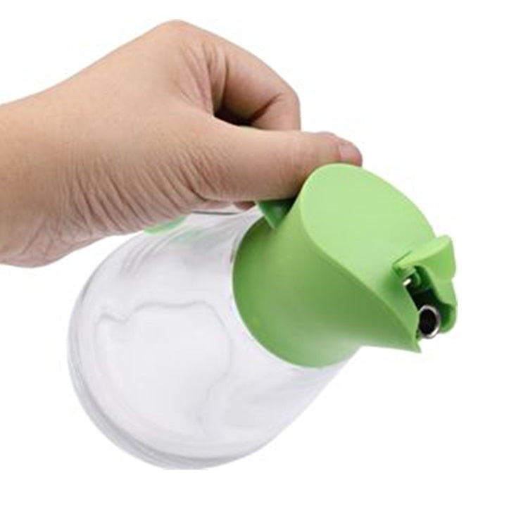 Green push-lid glass oil bottle shown with spout and nozzle view