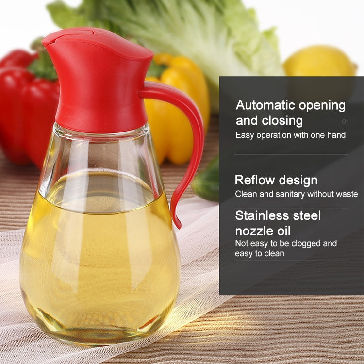 Red handled glass oil bottle with clear body filled with yellow oil