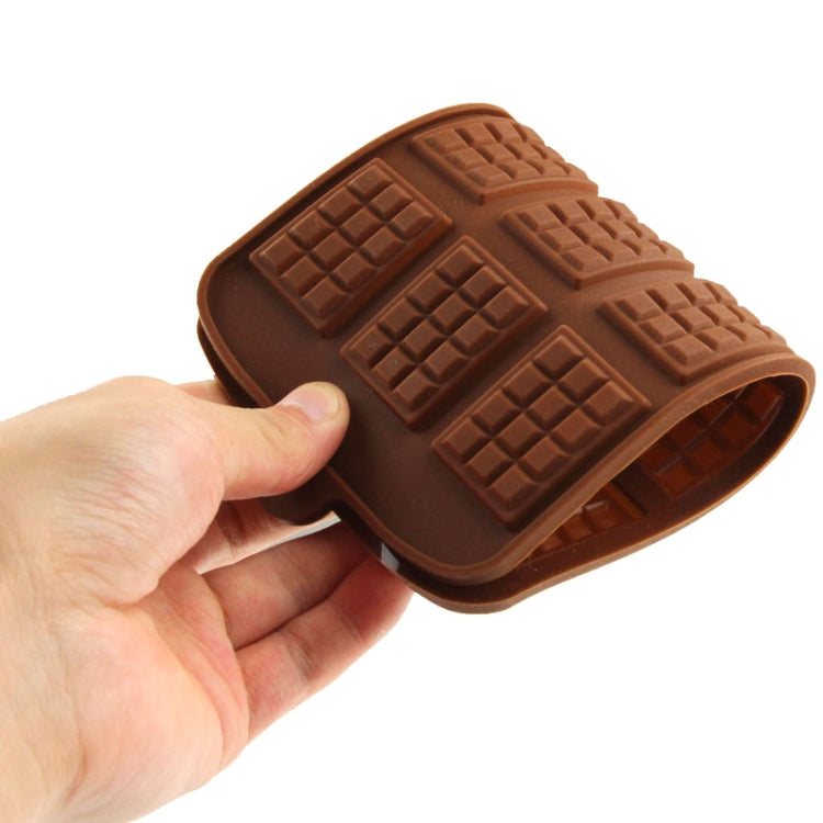 Brown silicone chocolate mold sheet with 12 square bar cavities, bent view in hand