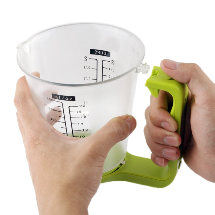 Hands holding green digital measuring cup with LCD weight and cup markings
