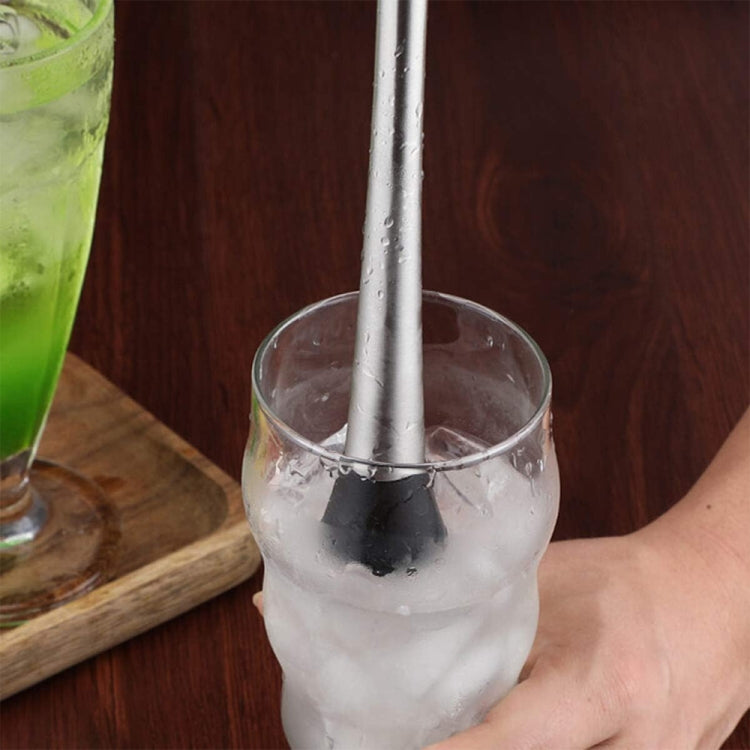 Stainless steel ice pick muddler pressing into ice in a clear glass