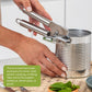 Stainless steel can opener in use on metal can, handheld spring lever, silver