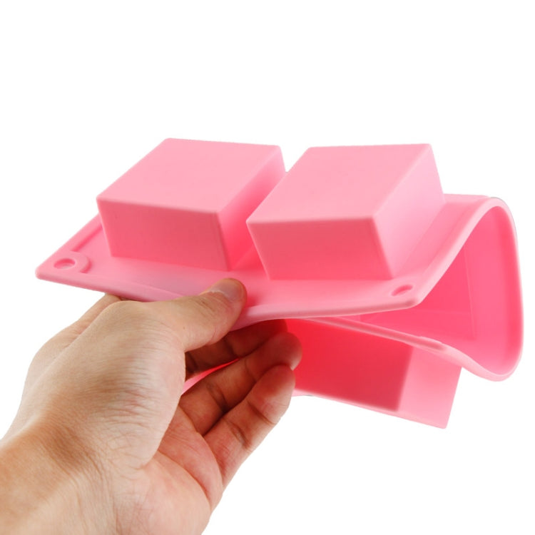 Pink silicone square cake mold with six cavities, held by hand