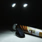 Dual-arm clip-on LED reading light switched on, shining onto a book on a tabletop