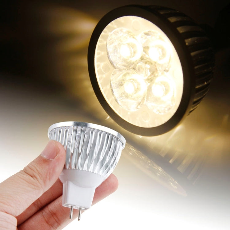 Warm white LED spotlight bulb with silver ridged reflector and two-prong base, held in hand