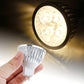 Warm white LED spotlight bulb with silver ridged reflector and two-prong plug base, shown close