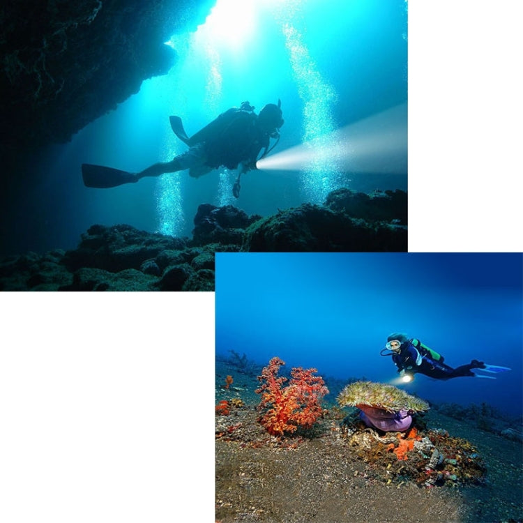 Underwater diver swimming with a bright handheld light near coral and rocks