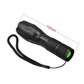 Black LED flashlight with lanyard strap, textured grip, and green tail cap; 135mm