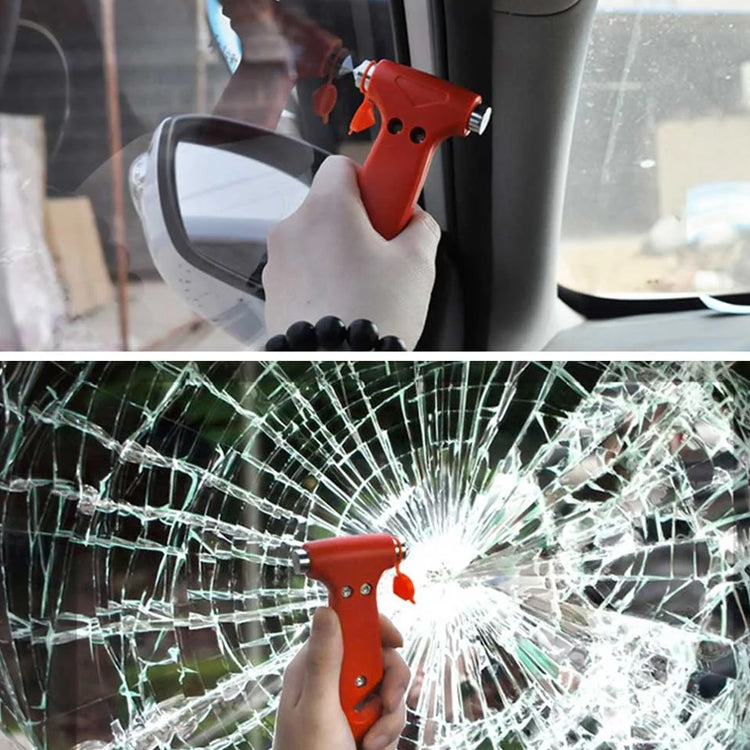 Hand holding orange emergency escape hammer at cracked car window glass