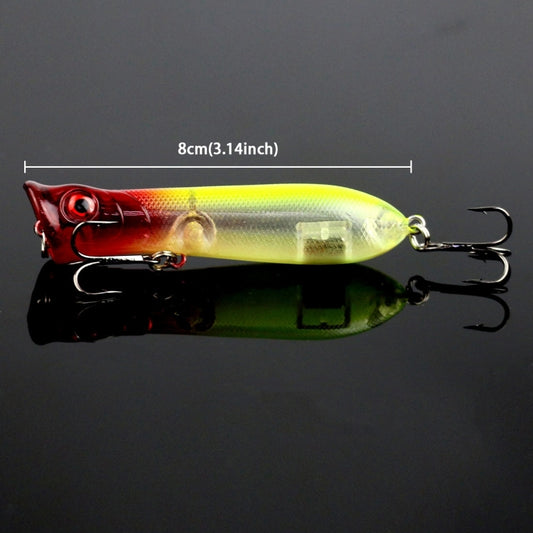 Surface fishing popper lure, red and yellow with black back, treble hooks attached.