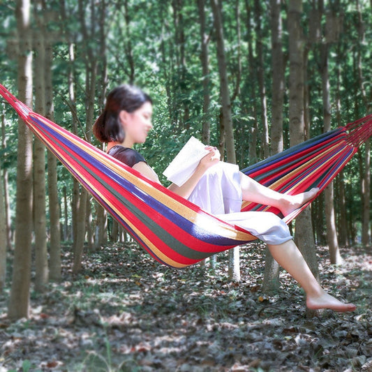 Red-and-blue striped canvas camping hammock in use, held taut between trees