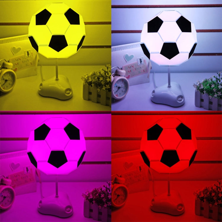 Soccer ball USB night light on stand, glowing in bright yellow and purple colors.