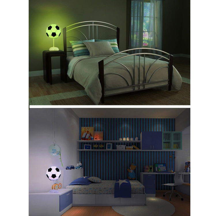 Soccer ball USB night light on stand, glowing green in a bedroom setting.