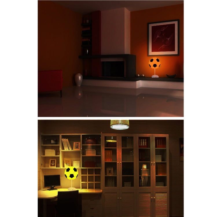 Soccer ball USB night light on stand, glowing orange in a room at night.