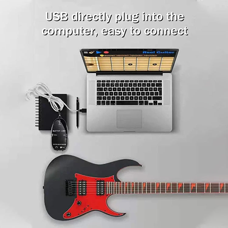 Black USB guitar interface adapter with cable, shown near a guitar and laptop
