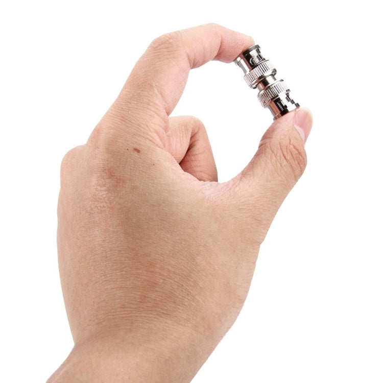 Hand holding a silver BNC coaxial male plug with knurled coupling nut