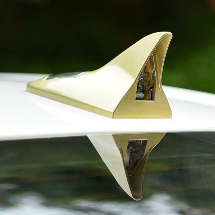 Gold solar shark fin high-mounted alarm light attached to a car roof edge