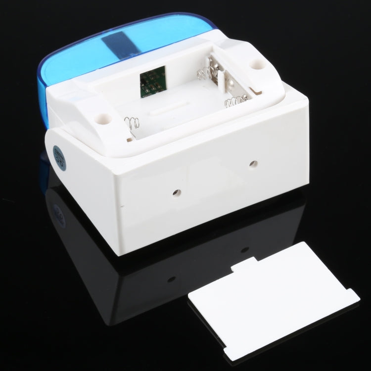 Wireless doorbell chime with open battery compartment, white housing and blue top