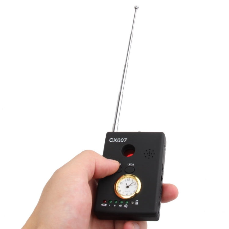 Hand holding black CX007 detector with LED controls, timer dial, and silver antenna
