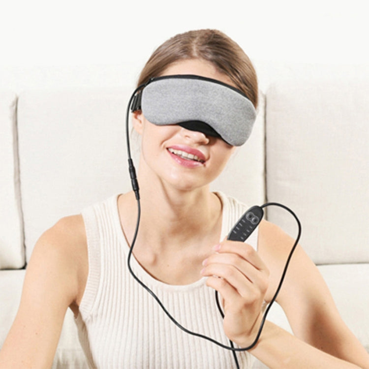 Grey heated sleep eye mask with wired controller held near the face