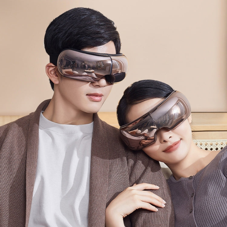 Eye massager worn on two people with curved visor over closed eyes.