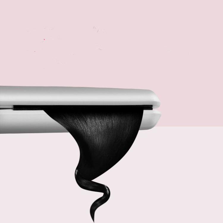 Hair curling iron close-up with dark hair on the curved plate