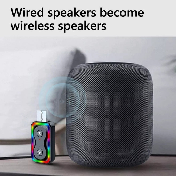 Bluetooth audio adapter connected to a dark gray portable speaker with multicolor LEDs