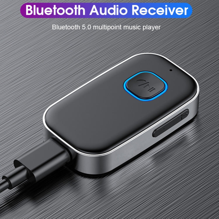 Bluetooth audio receiver with blue-ring button, dark metal body and AUX plug connected
