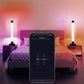 Two color-changing LED light tubes on desktop stands in a bedroom setting