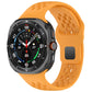 Orange perforated silicone watch band with square buckle, attached to a smartwatch