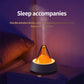 Glittering humidifier diffuser with orange light glow beside a pillow