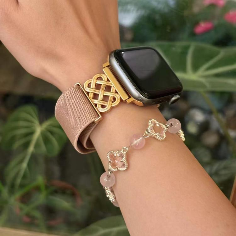 Apple Watch band in dusty pink twill with a gold-tone Chinese knot magnetic buckle, worn on wrist