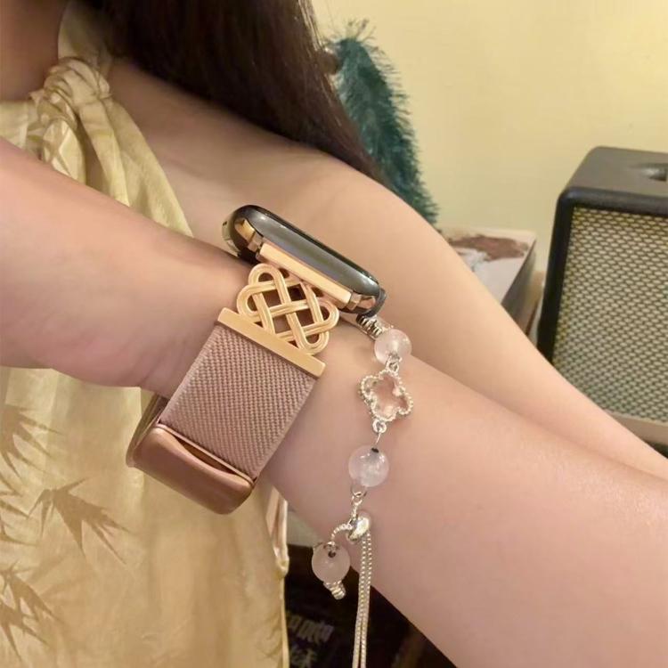 Dusty pink twill Apple Watch band with a gold-tone Chinese knot magnetic buckle, shown on wrist