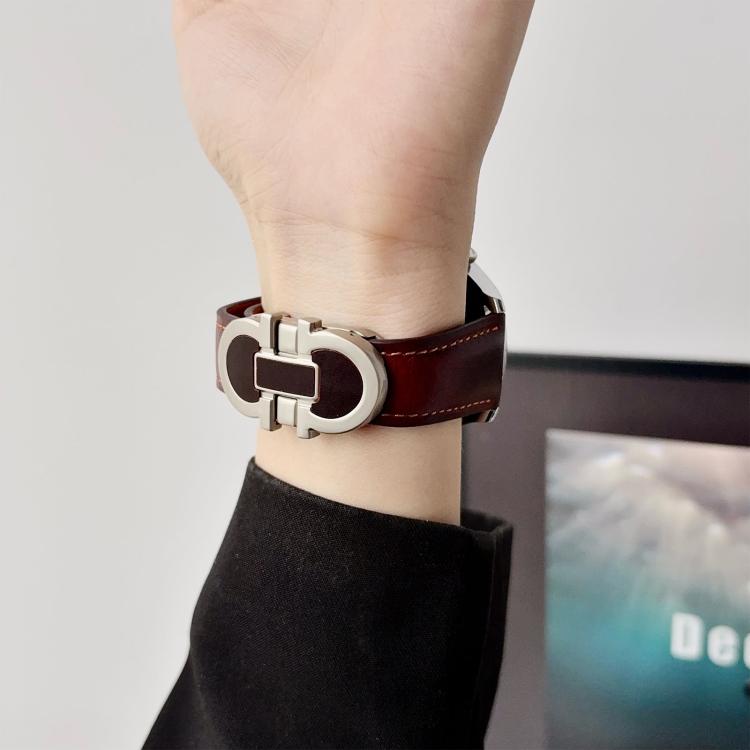 Dark brown leather watch band with a silver double-G magnetic buckle, worn on the wrist