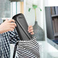 Black hard instrument case carried with shoulder strap over striped clothing