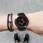Men's watch on wrist with black dial, red markers, and metal bracelet.