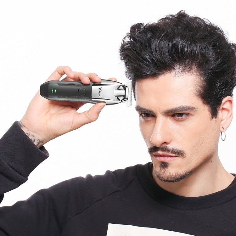Cordless electric hair clipper held near hair, showing metallic blade for trimming