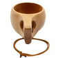 Wooden cup with two side openings and long cord tied around the sides