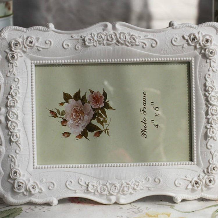 White ornate carved picture frame with raised floral border and rose bouquet insert