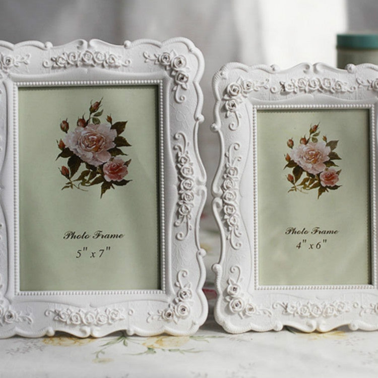 Two white carved floral picture frames side by side, each with rose bouquet insert