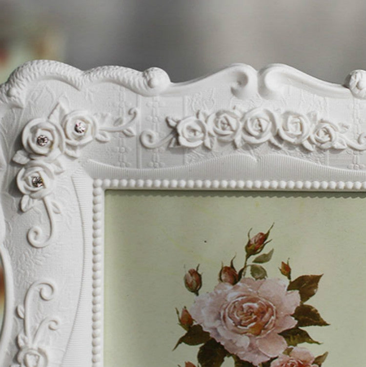 White carved rose picture frame top detail with raised floral rosettes