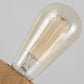 Clear glass bulb with visible filaments on a wooden geometric lamp base