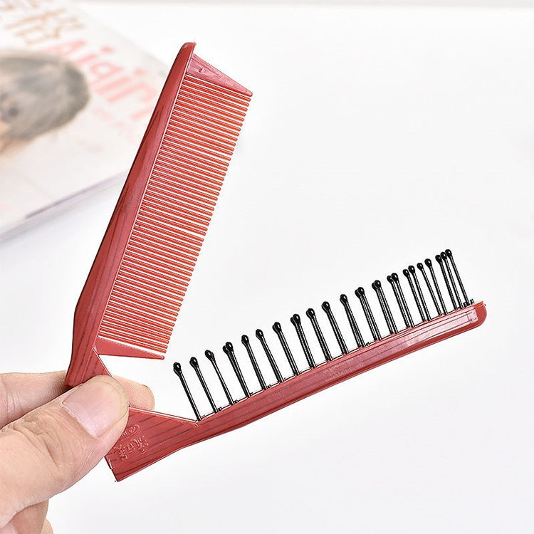 Red travel folding comb with fine teeth and massage pins, held in hand