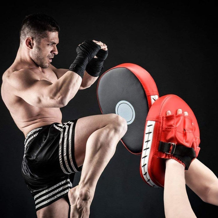Red and black martial arts hand target pad with wrist strap in use