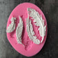 Pink silicone mold showing five raised feather designs, seen from above