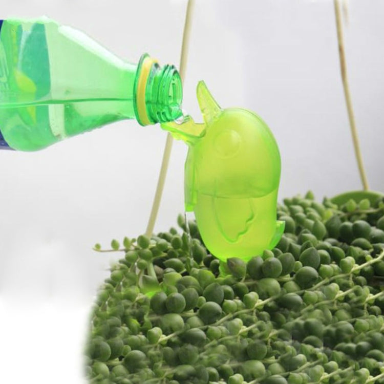Green bird-shaped sprinkler releasing water above succulent plants