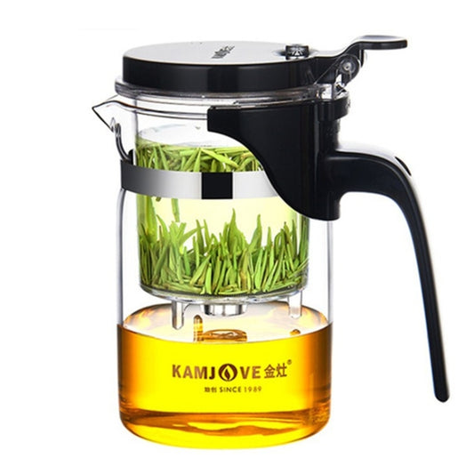 Glass tea teapot with black lid, press strainer, and handle; green tea leaves inside.
