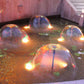 Hemisphere fountain water jets from multiple copper-colored nozzles