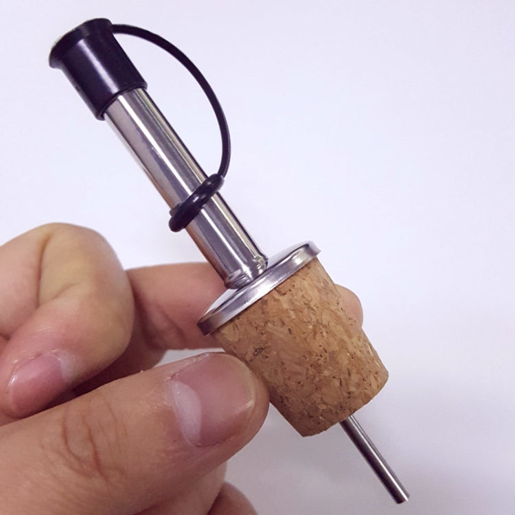Hand holding wine cork stopper wine diversion spout dispenser with black cap and metal spout