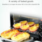 Black mini oven with baked tarts and bread rolls on the rack and tray